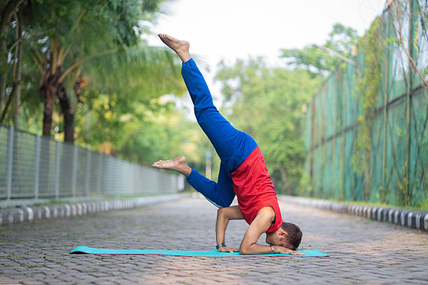 Captured in a serene outdoor setting, this image shows a yoga practitioner balancing in the advanced inversion known as Pincha Mayurasana. With perfect form and strength, the pose conveys the essence of concentration, inner balance, and physical discipline. Suitable for health, fitness, spiritual, or lifestyle stock collections.