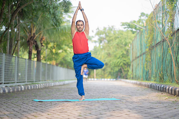 istock Young man standing in tree yoga pose in park 2219038688