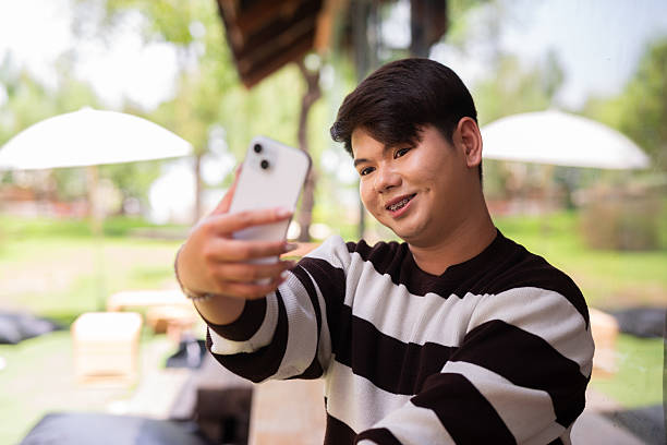 istock Young cute gay man sitting outdoors in cafe restaurant 2219039272