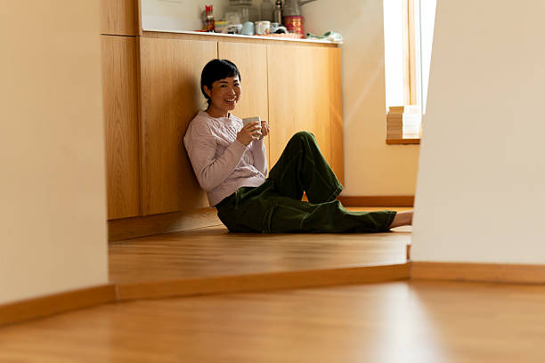 istock Smiling woman relaxing on kitchen floor with mug 2219039967