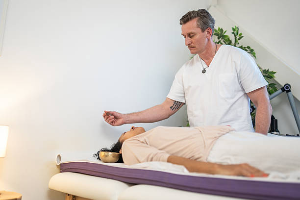 Beautiful woman is lying on stomach on a massage table in a salon, and a massage therapist is massaging her feet.