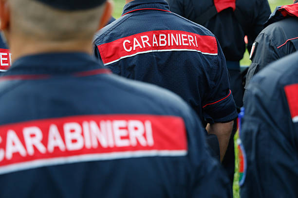 Rear view of several Italian Carabinieri officers standing in uniform.