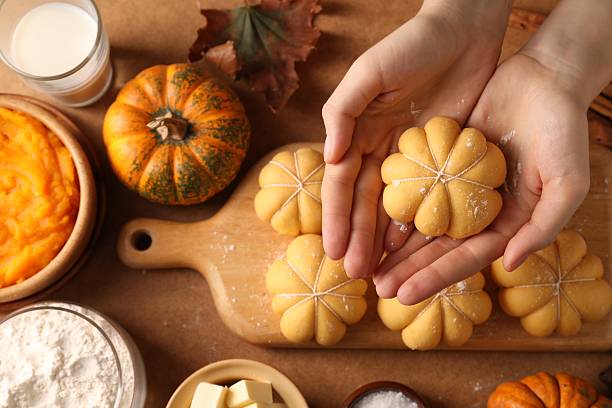 istock Woman making pumpkin shaped buns at brown table, top view 2219047742