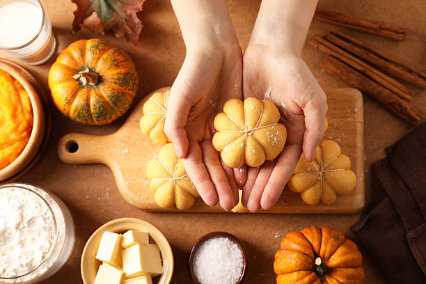 istock Woman making pumpkin shaped buns at brown table, top view 2219047747