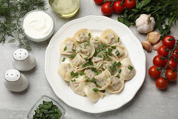istock Delicious pelmeni with green onion served on grey textured table, flat lay 2219048515
