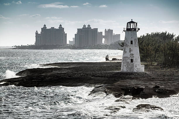 Lighthouse, Atlantis resort hotel in silhouette in the distance, early morning, Paradise Island, Nassau, Bahamas, photographed from a cruise ship as it enters the harbor.  Lighthouse in a state of disrepair.  Photographed March 3, 2025.
