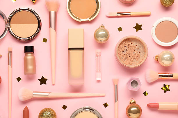 Different makeup brushes, decorative cosmetics and Christmas decor on pink background, flat lay
