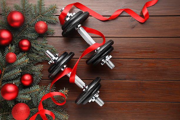 istock Dumbbells, fir tree branches and Christmas baubles on wooden table, flat lay. Space for text 2219049087
