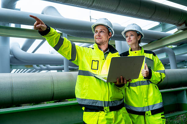 istock Two petrochemical or gas workers or technicians use laptop to work near pipe network with man also point to left direction. 2219049392