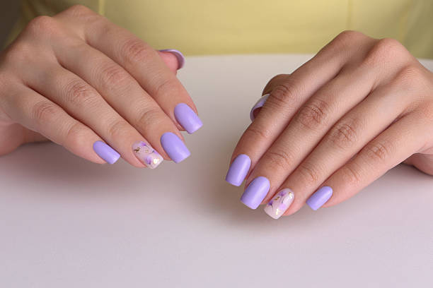 istock Female hands with purple manicure nails 2219051120