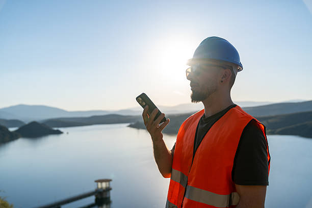 istock Engineer using smartphone near lake at sunset for workplace safety 2219052915