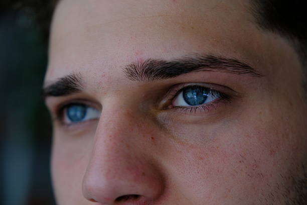 istock Young man with blue eyes looking out the windowv 2219053319
