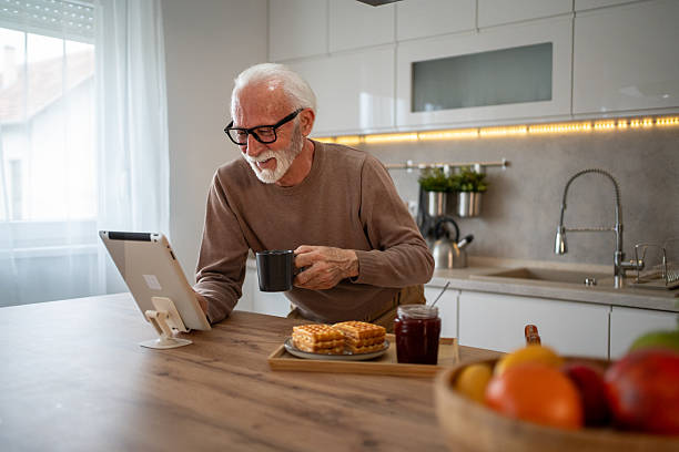 istock Senior man enjoying breakfast and browsing internet on tablet in kitchen 2219054951