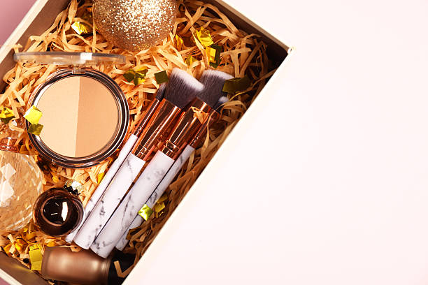 istock Makeup brushes, decorative cosmetics, perfume and Christmas decor in box on pink background, top view. Space for text 2219055011