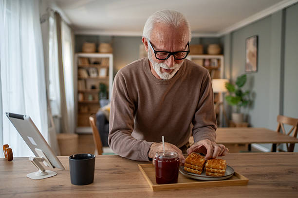 istock Senior man enjoying breakfast and using digital tablet at home 2219055098
