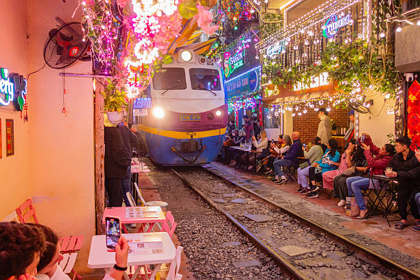 Hanoi, Vietnam- February 5, 2025: Train passing through the iconic narrow Hanoi Train Street lined withourists taking pictures the fast-moving train.
