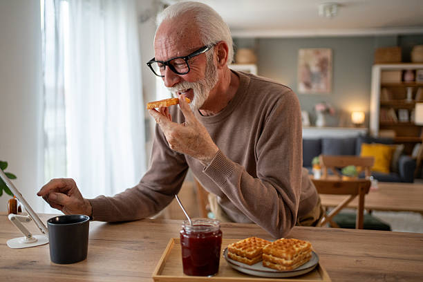 istock Senior man enjoying breakfast and browsing internet on tablet at home 2219055208
