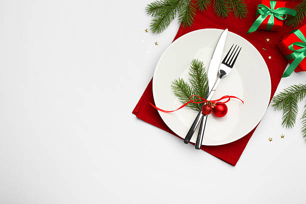 istock Christmas table setting with plate, cutlery, napkin and festive decor on white background, flat lay. Space for text 2219055275