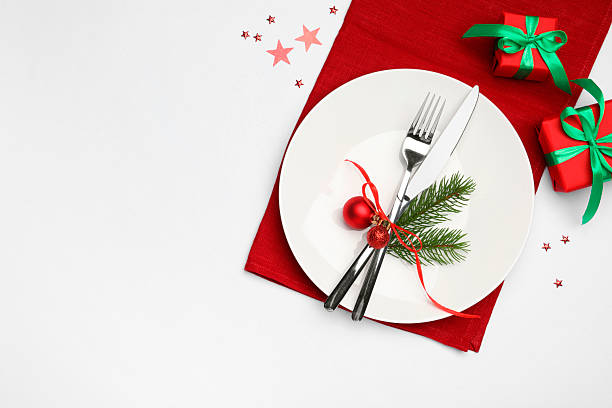 istock Christmas table setting with plate, cutlery, napkin and festive decor on white background, flat lay. Space for text 2219055302