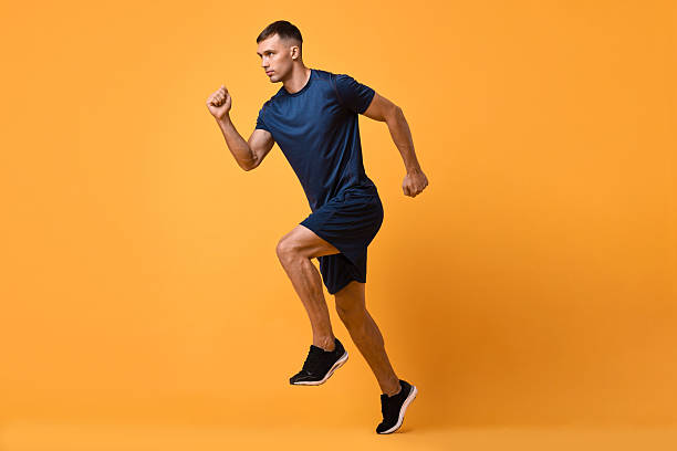 istock Man in sportswear running on orange background 2219055521