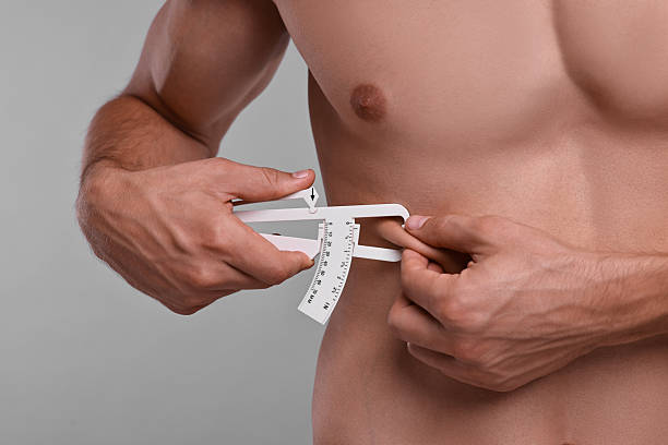 istock Man measuring body fat with caliper on grey background, closeup 2219055783