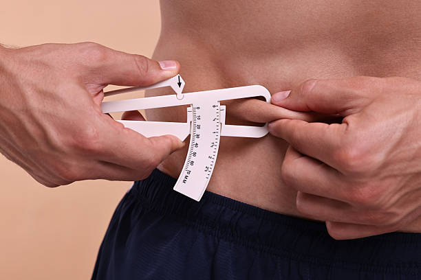 istock Man measuring body fat with caliper on beige background, closeup 2219055784