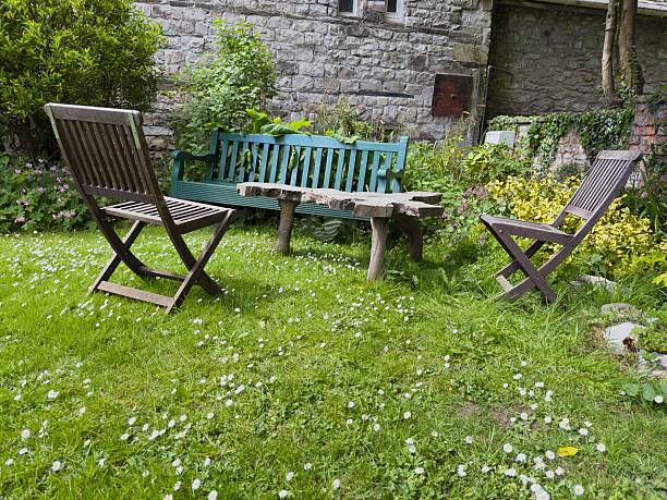 istock Chairs and bench around rustic wooden table in cottage garden. 2219060834