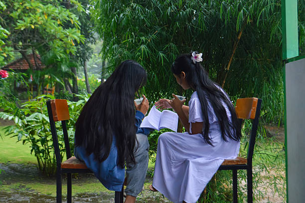 Girls stay at the edge of the shelter, combining study and refreshment, avoiding the pouring rain outside.