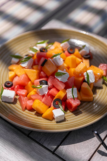 poolside lunch with melon feta salad served at resort swimming pool sun lounge deck chairs