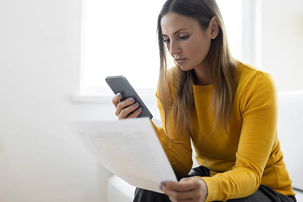 istock Woman checking phone and paper seriously 2219065467
