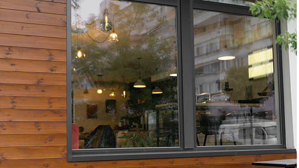 Cozy cafe interior view through a large window on a rainy afternoon with warm lighting and wooden accents