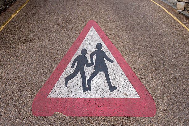 Warning Sign Depicting School Crossing on a Rough Textured Road Surface