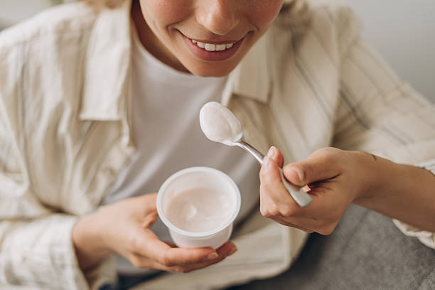 istock Top view smiling, young woman enjoying yogurt cup at home closeup, selective focus 2219081665