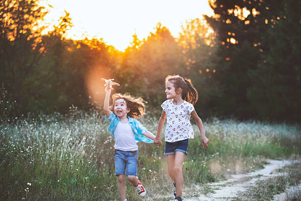 istock Smiling friends enjoying the sunset while running with a classic airplane toy 2219092444
