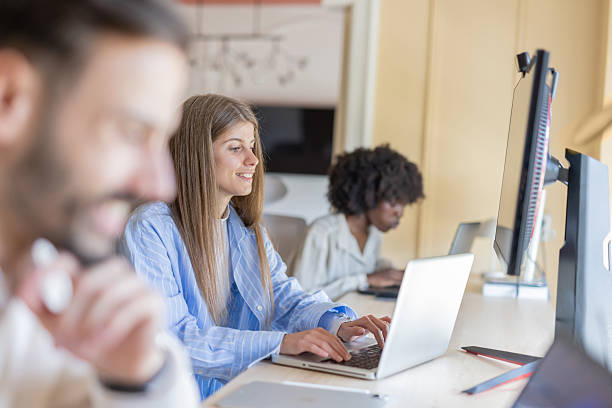 istock Young woman smiles while working on her laptop in office. 2219100143
