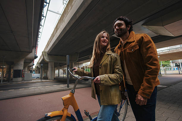 istock Young couple walking with bicycle in urban environment under a bridge in Rotterdam 2219100570