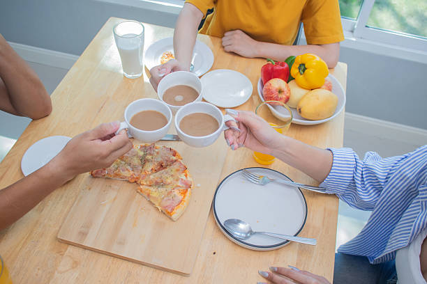 istock Two Asian men and women sit at home with breakfast smiling, enjoying drinks, a combination of wellbeing, relaxation and digital connection. 2219115302