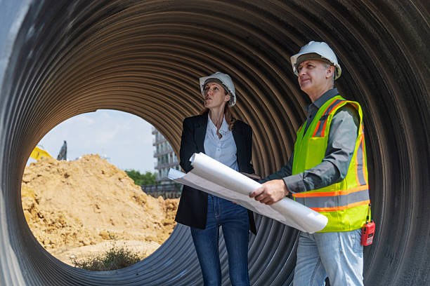 istock Two engineers in safety gear stand inside a large corrugated pipe at a construction site 2219116835