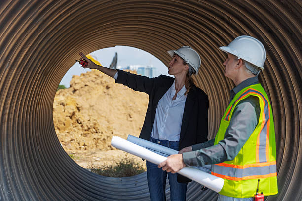 istock Two engineers in safety gear stand inside a large corrugated pipe at a construction site 2219116839