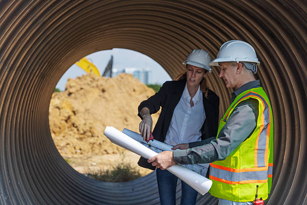 istock Two engineers in safety gear stand inside a large corrugated pipe at a construction site 2219116847