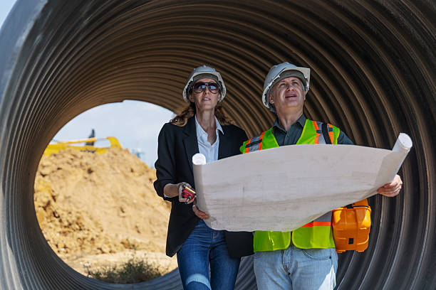 istock Two engineers in safety gear stand inside a large corrugated pipe at a construction site 2219116851