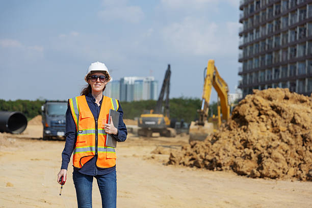 istock A female construction engineer in a hard hat and safety vest stands confidently at an active construction site 2219116913