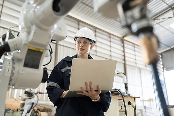 istock Robotic arm, Robotic manufacturing industry. Woman engineer working with laptop computer for setup, install, maintain, repair mechanism of operation of robotic arm in workshop 2219117368