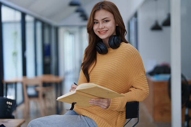 istock A smiling young woman writes in a notebook while wea headphones indoors. 2219118122