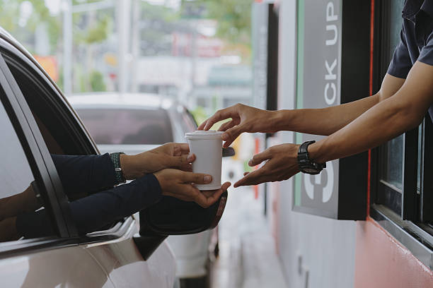 istock A customer picks up food in his car during rush hour from a drive-thru delivery worker. 2219120518