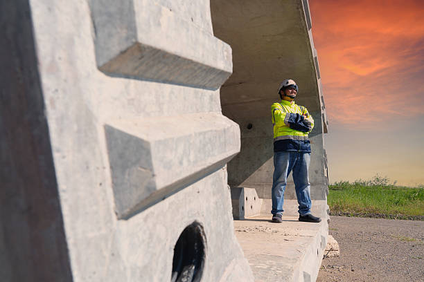 Asian architect engineer wearing safety uniform surveying and working at building structure checking blueprints construction site road general job details business concept architecture street