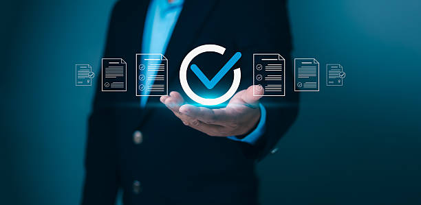 istock Business person holding a checkmark icon surrounded by document lists, symbolizing successful completion, quality assurance, and compliance. Ideal for approval, verification, and certification. 2219123656