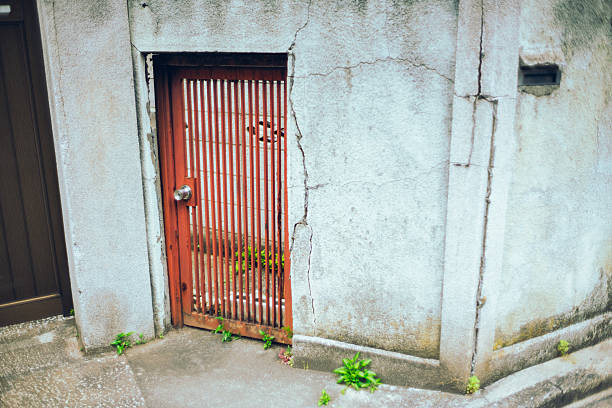 Neglected red gate and decaying concrete wall