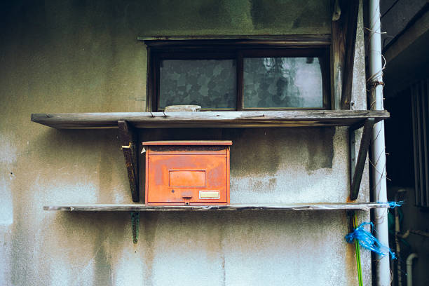 Rusty red mailbox on a weathered wooden shelf