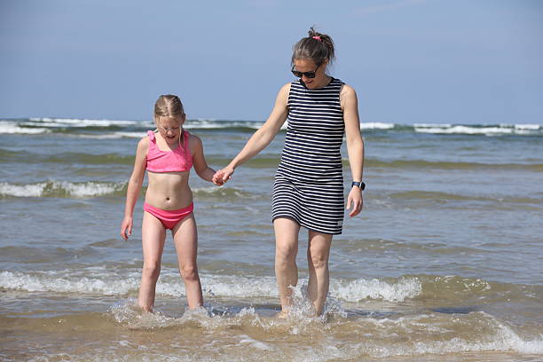 istock Mother and daughter walking in sea 2219127882